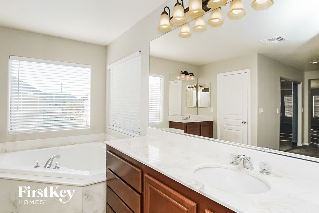 a bathroom with a large mirror and a tub and a sink