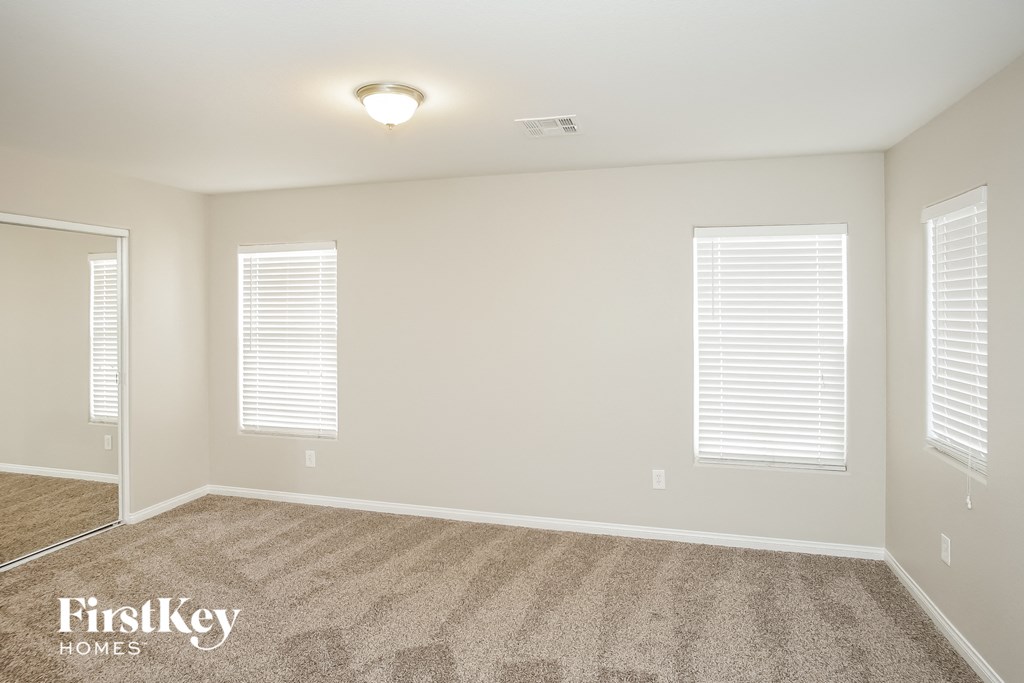 a empty room with two windows and a carpeted floor