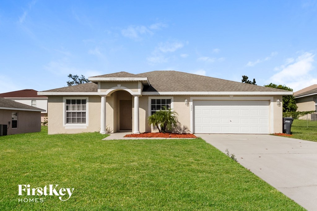 a beige house with a garage and a lawn
