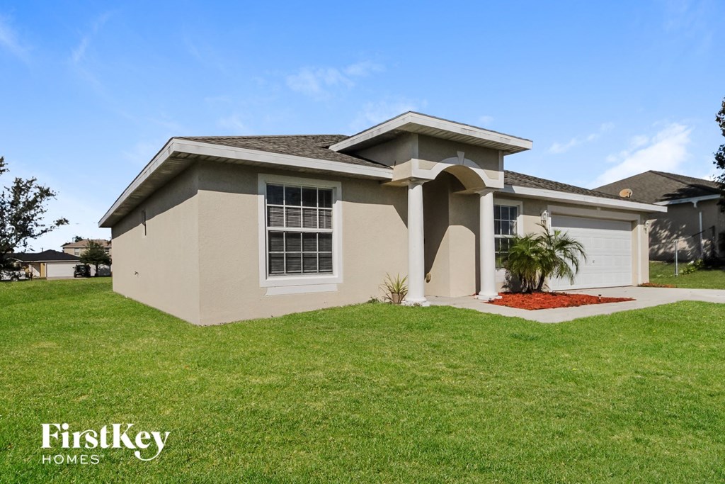 a beige house with a lawn and a palm tree
