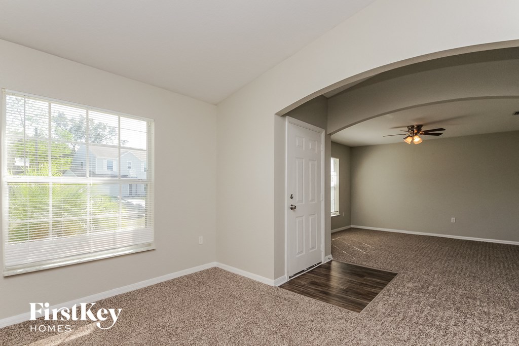 an empty living room with a large window and a white door