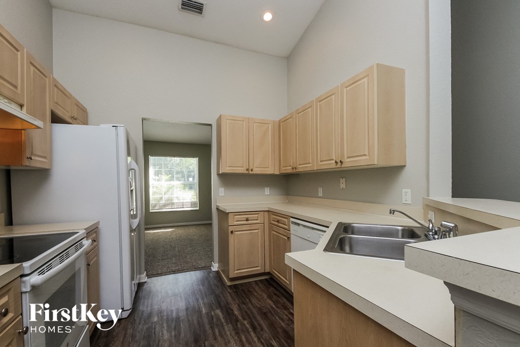 a kitchen with white counter tops and wooden cabinets and a refrigerator and sink