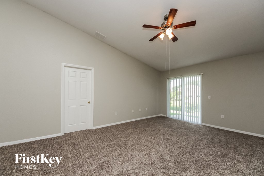 the spacious living room with ceiling fan and window