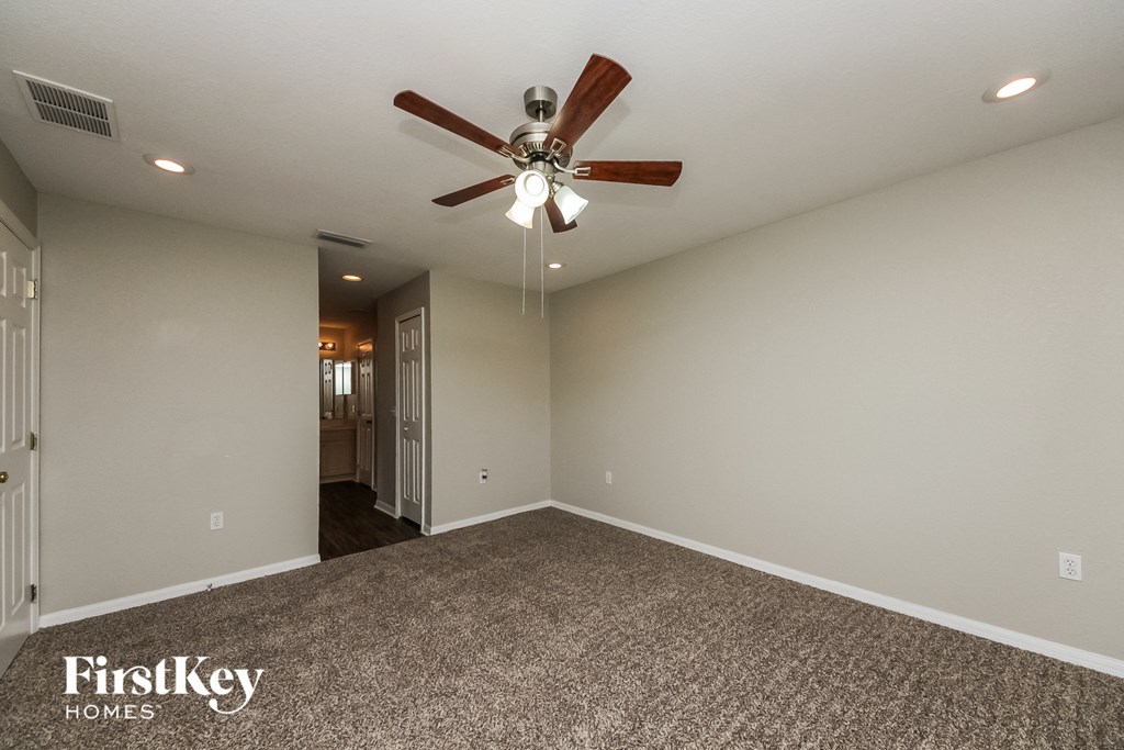 the master bedroom has a ceiling fan and a carpeted floor