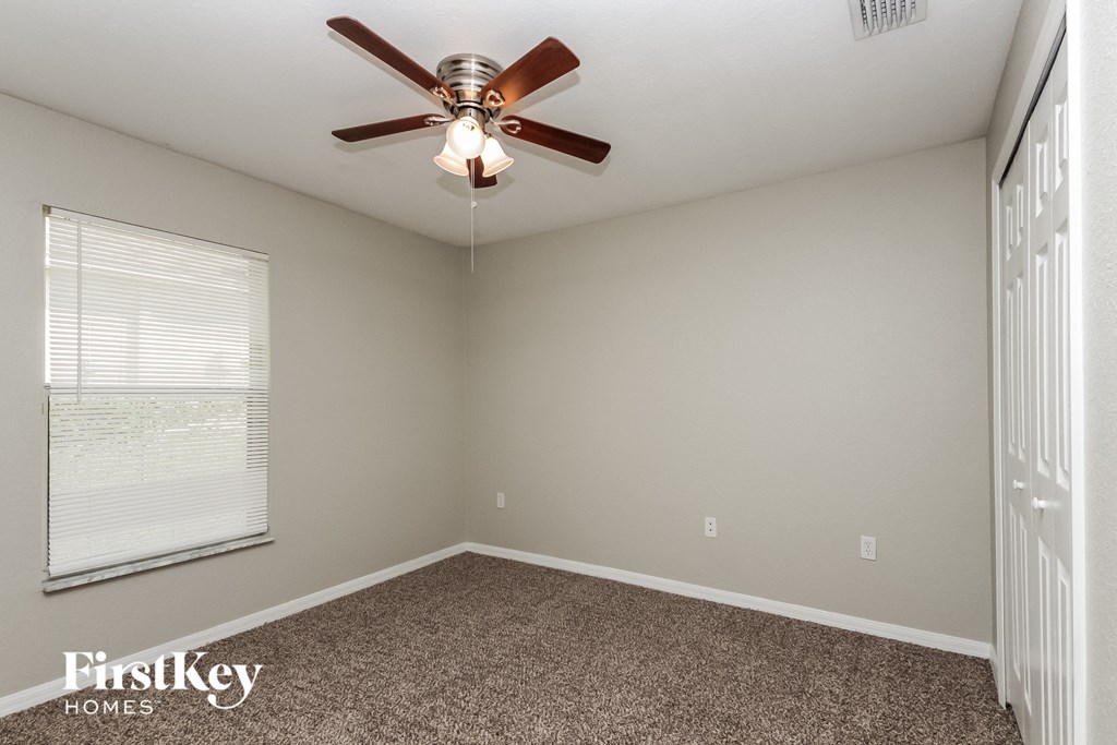 the bedroom has a ceiling fan and a window