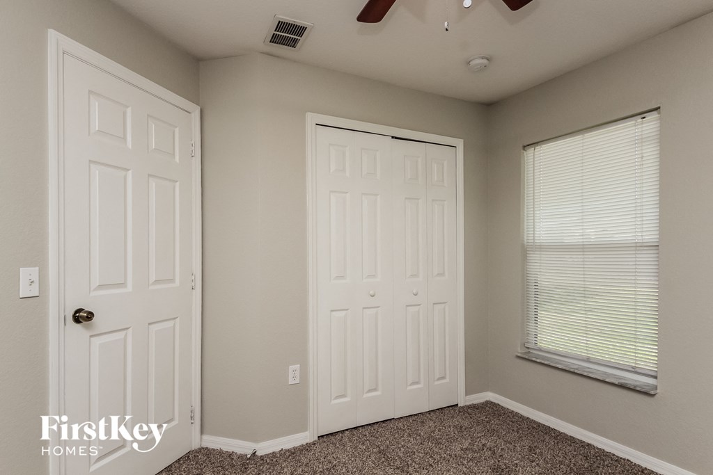 a bedroom with two closets and a window and two doors