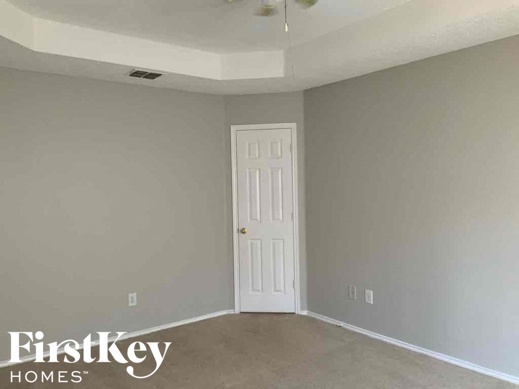 a bedroom with a white door and gray walls and a carpeted floor