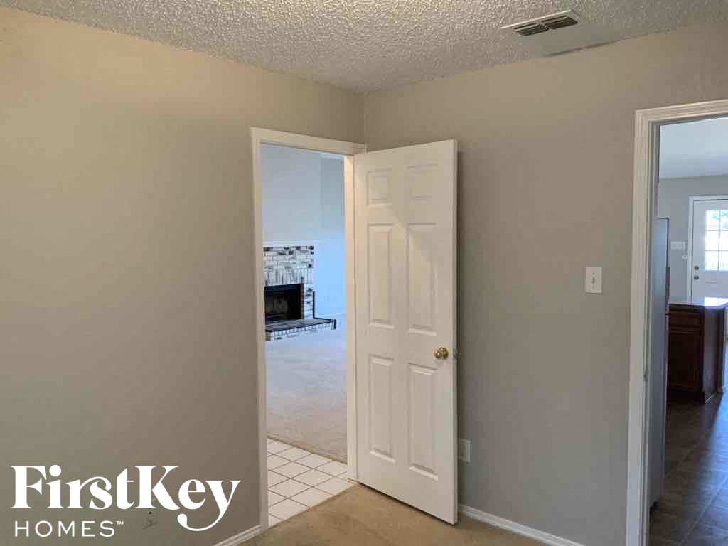 a room with a door open to a hallway and a door to a bedroom