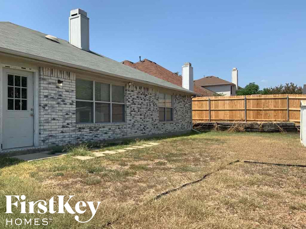 a backyard with a wooden fence in front of a house
