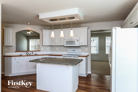 A kitchen with white cabinets and a granite countertop.