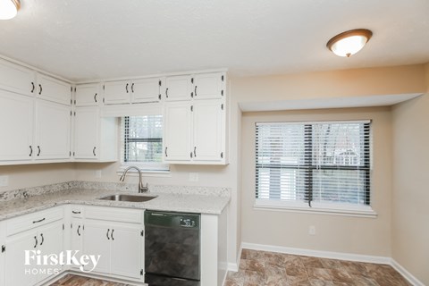 A kitchen with white cabinets and a granite countertop.