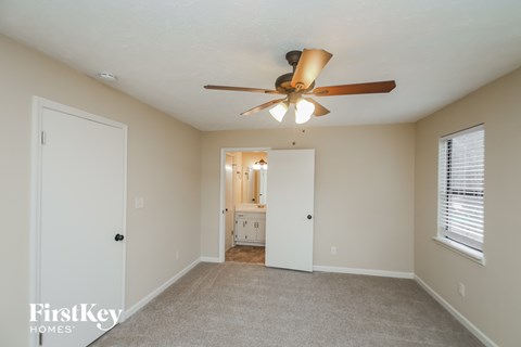 A spacious room with a ceiling fan and a carpeted floor.