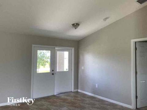 an empty living room with a door and a window