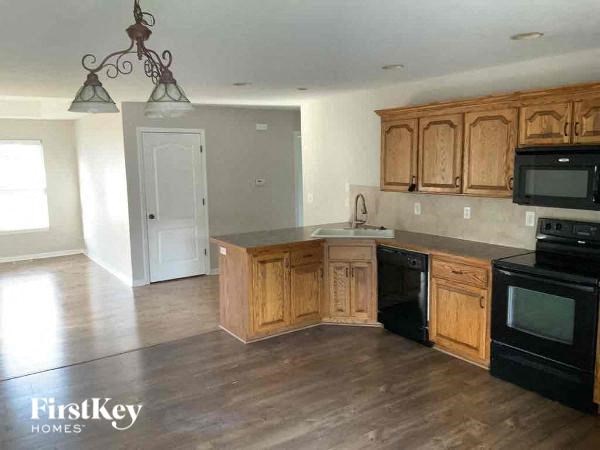 an empty kitchen with wooden cabinets and black appliances