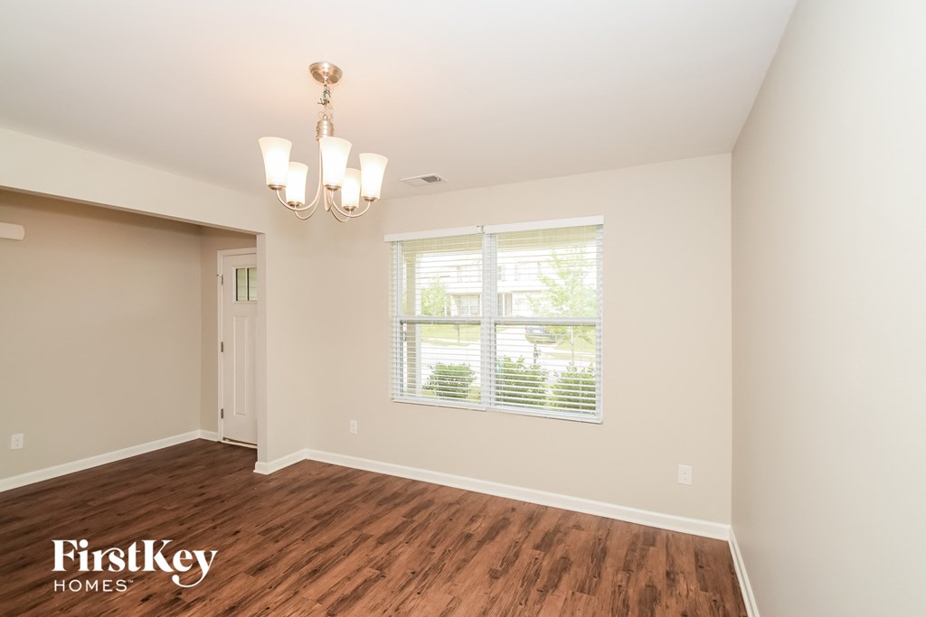a living room with a large window and wooden floors and a chandelier