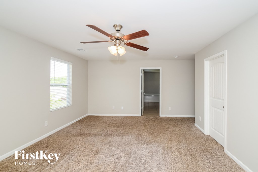 a spacious living room with carpet and a ceiling fan