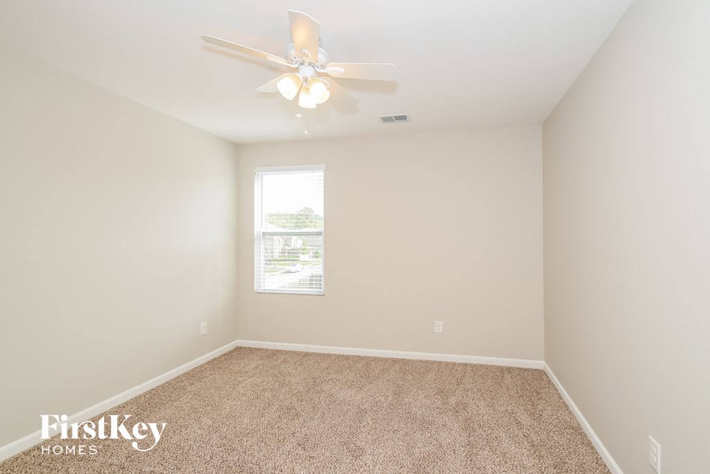 a spacious room with carpet and a ceiling fan