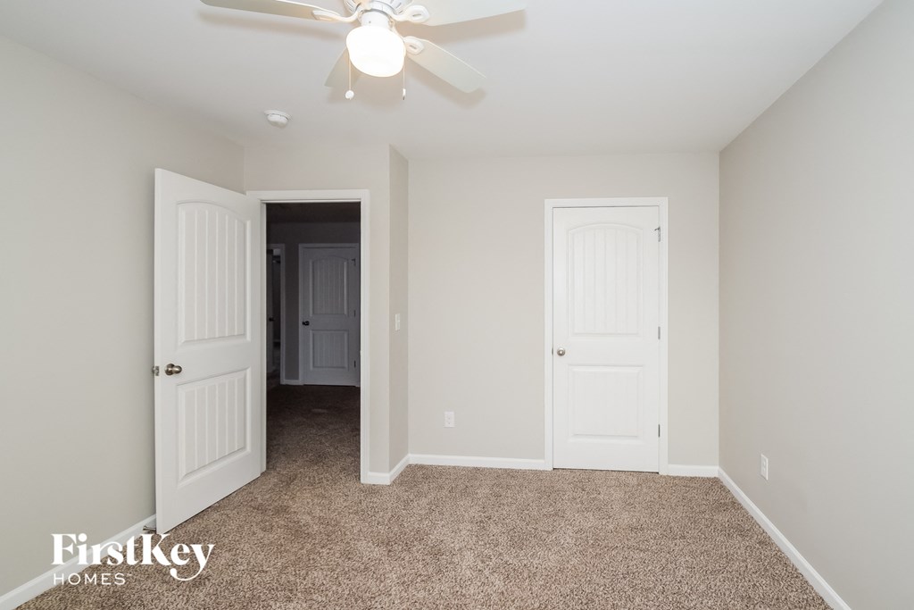 a bedroom with two doors and a ceiling fan