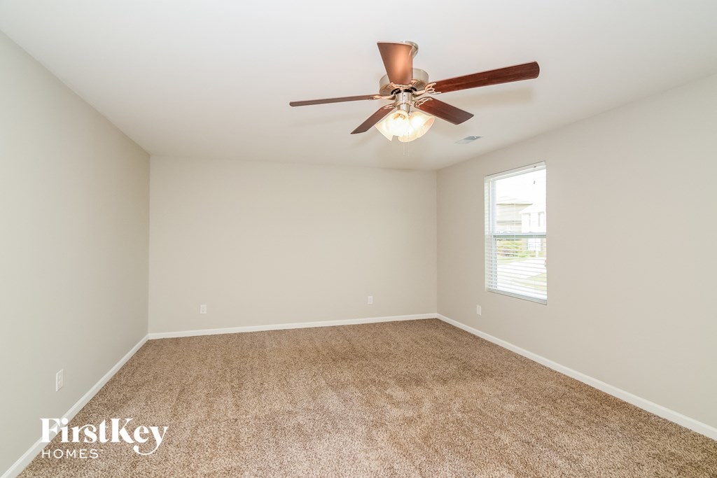the spacious living room with ceiling fan and carpet
