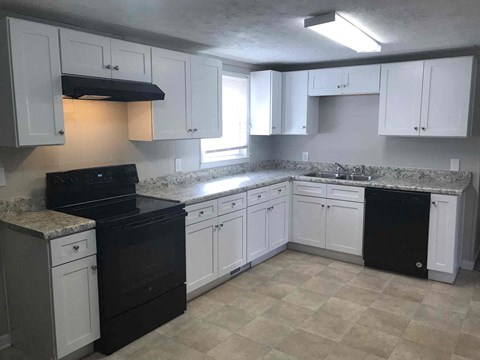 A kitchen with black appliances and white cabinets.