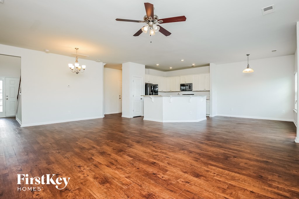A spacious room with wooden floors and a ceiling fan.
