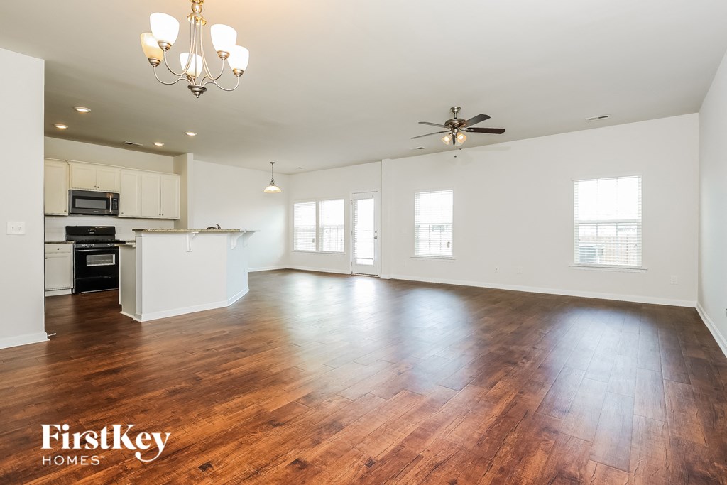 A spacious living room with wooden floors and a ceiling fan.