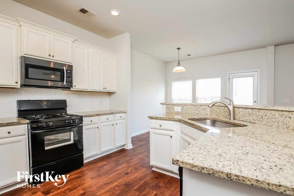 A kitchen with a granite counter top and a black stove top oven.