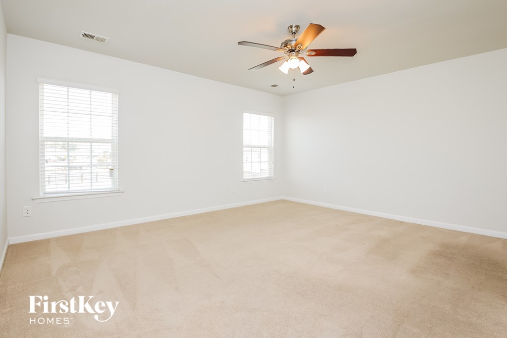 A room with a ceiling fan and two windows.