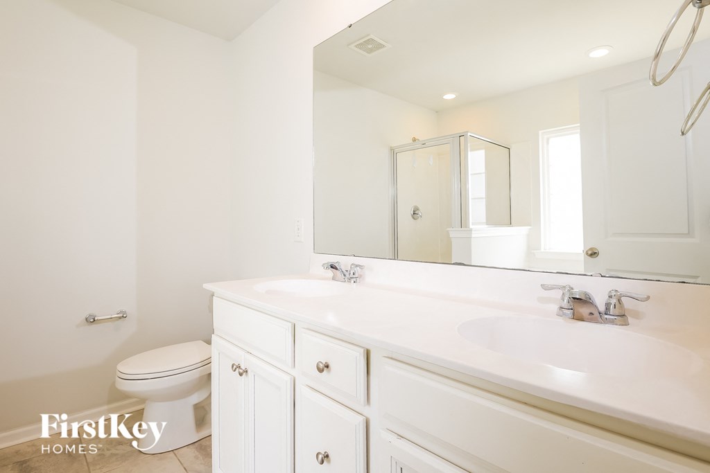 A white bathroom with a toilet, sink, and mirror.