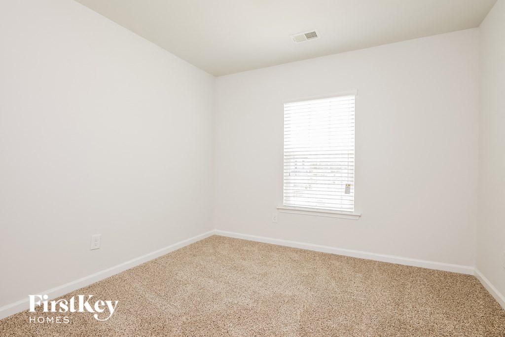 A room with a carpeted floor and a window with blinds.