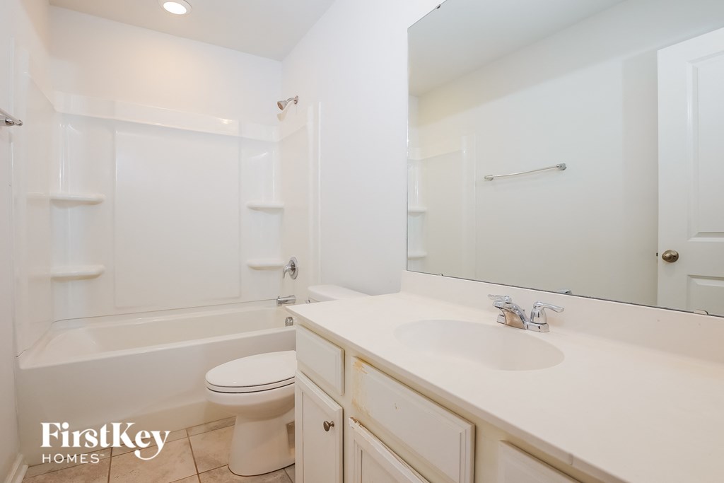 A white bathroom with a toilet, sink, and bathtub.