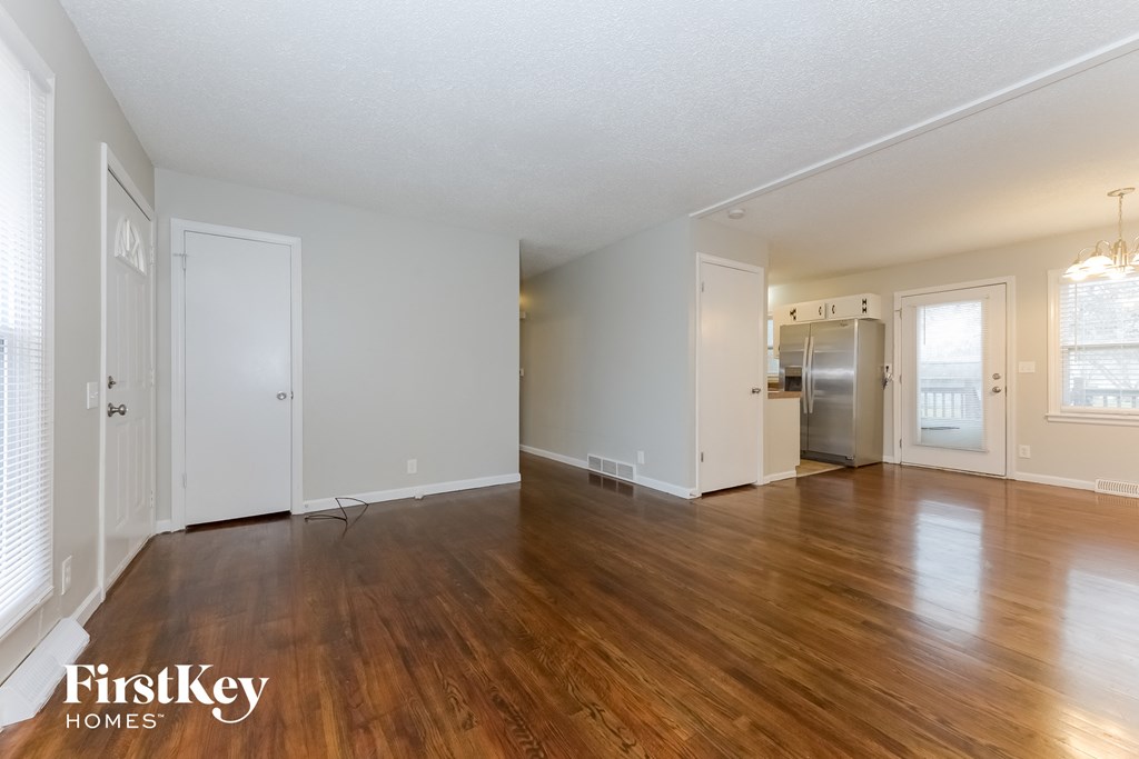 A spacious empty room with wooden floors and white walls.