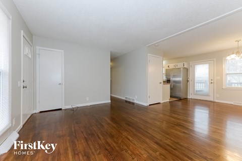 A spacious empty room with wooden floors and white walls.