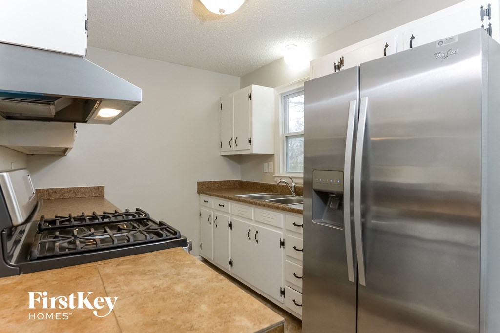 A kitchen with a stove, refrigerator, and cabinets.
