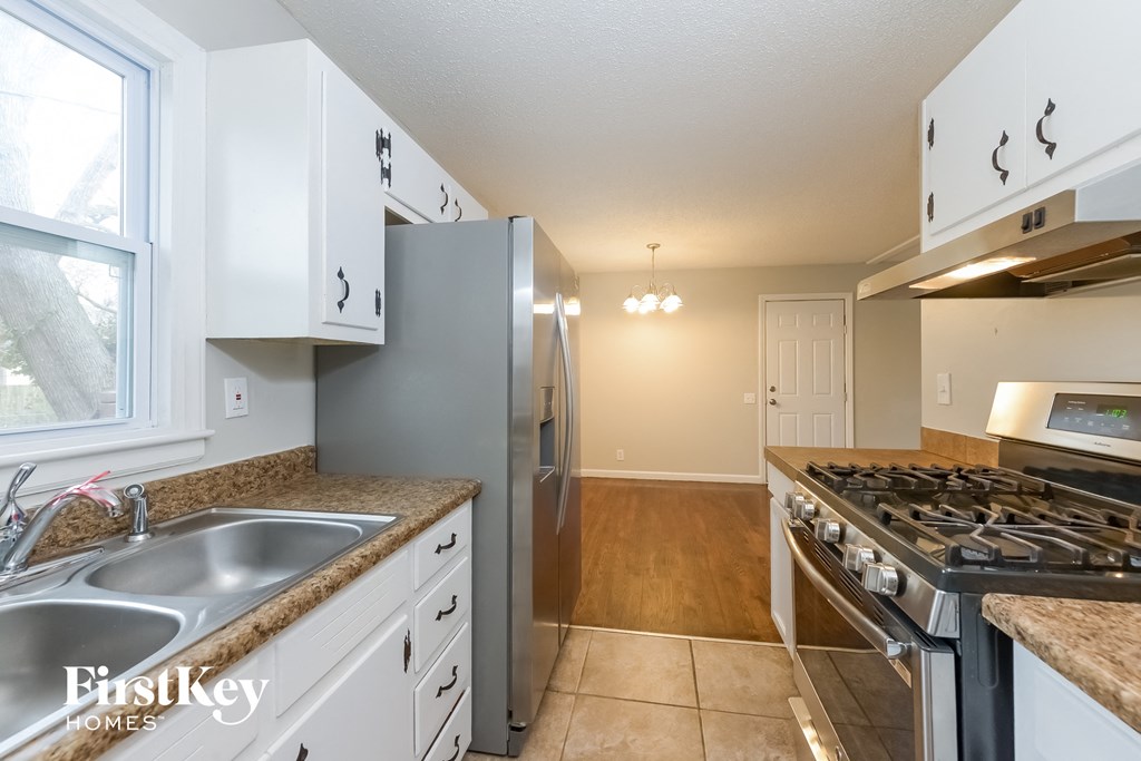 A kitchen with white cabinets and a stainless steel refrigerator.