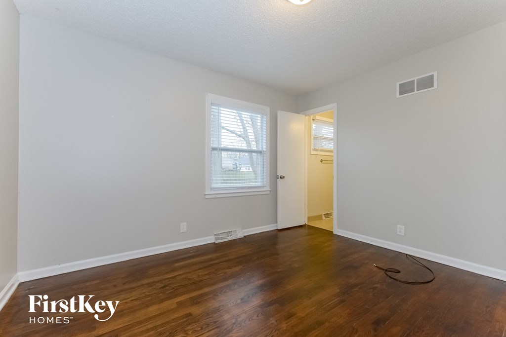A room with wooden floors and a window with blinds.