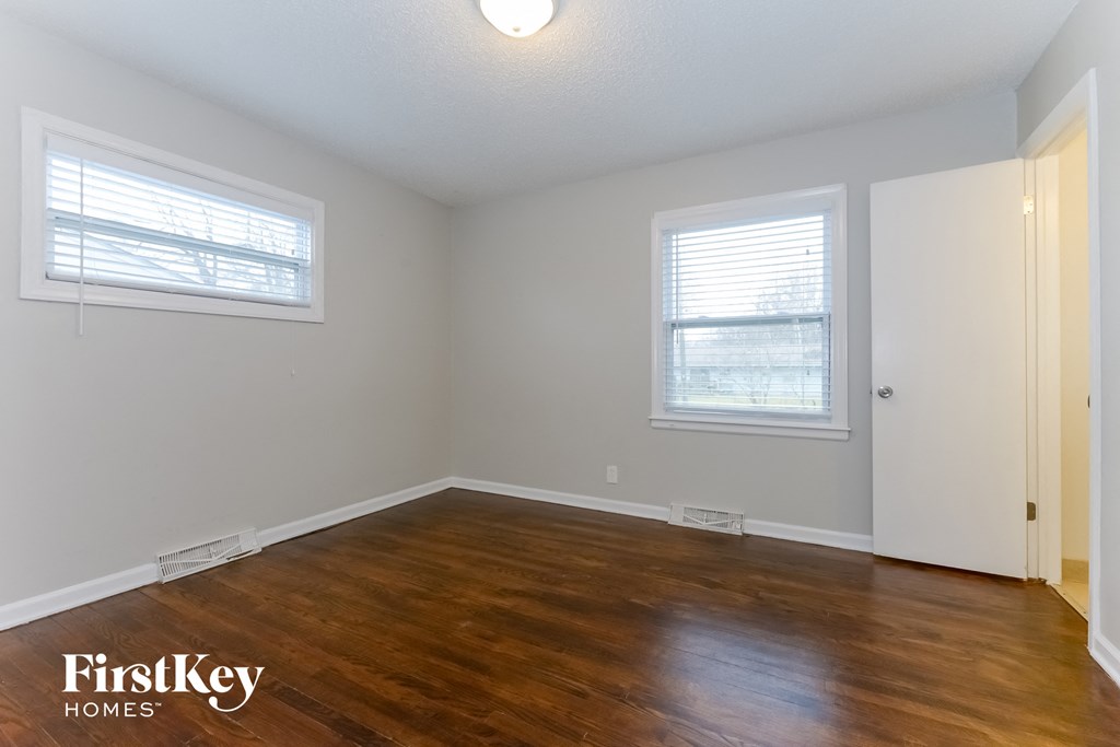 A room with wooden floors and two windows.