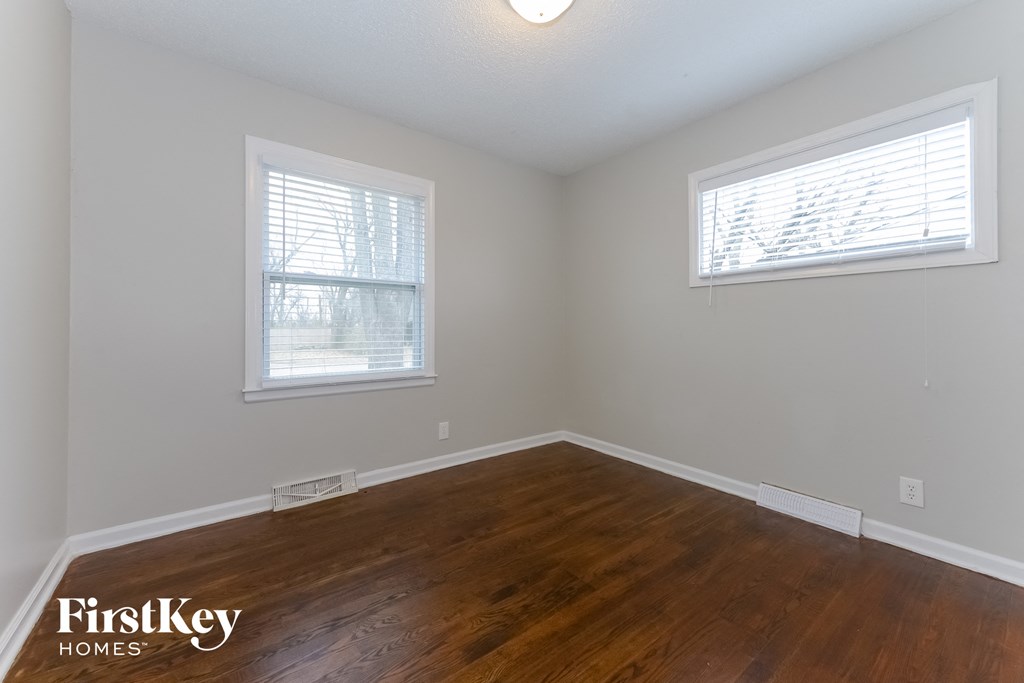 A room with wooden floors and two windows.