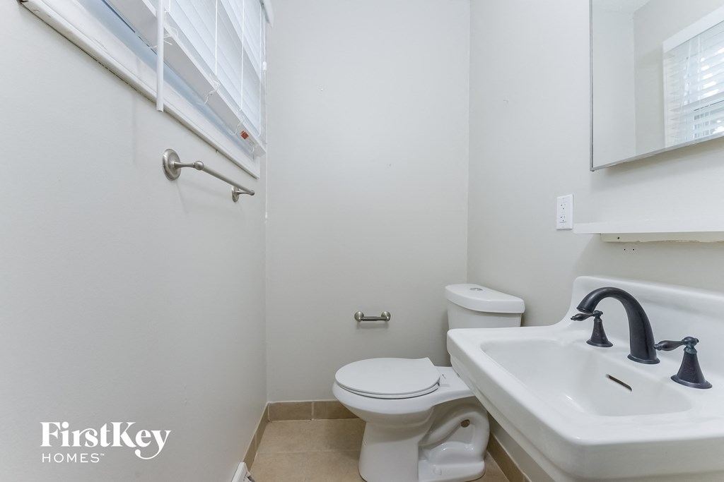 A white bathroom with a toilet, sink, and mirror.