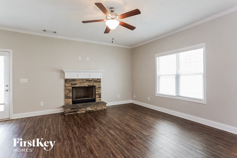 A spacious room with a fireplace and a ceiling fan.