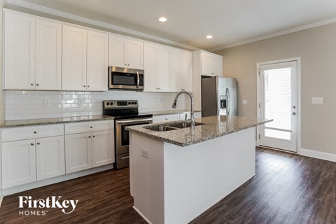 A kitchen with white cabinets and a granite countertop.