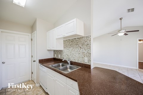 a kitchen with a sink and white cabinets and a ceiling fan