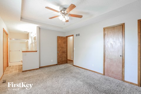 A spacious room with a ceiling fan and a carpeted floor.