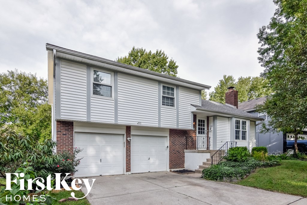 A house with a garage and a tree in front of it.