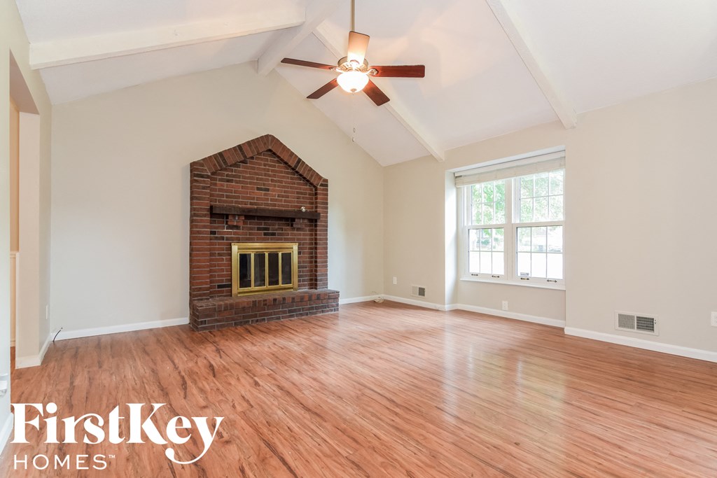 A room with a brick fireplace and wooden floors.