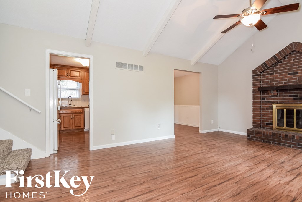 A spacious room with a fireplace and a ceiling fan.