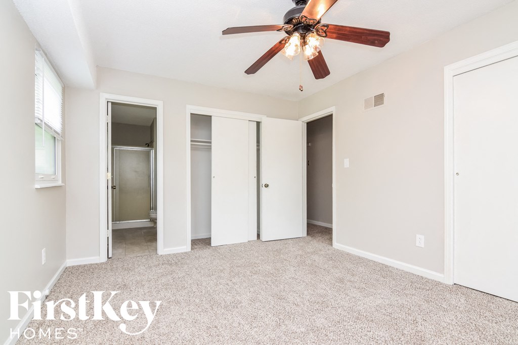 A spacious room with a ceiling fan and carpeted floor.