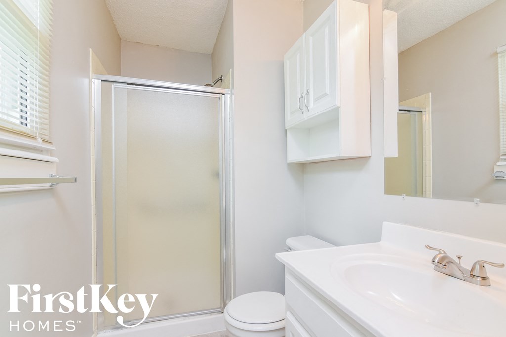 A white bathroom with a toilet, sink, and shower.