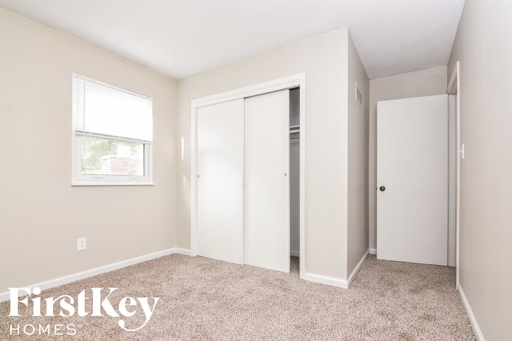 A bedroom with a carpeted floor and a window.