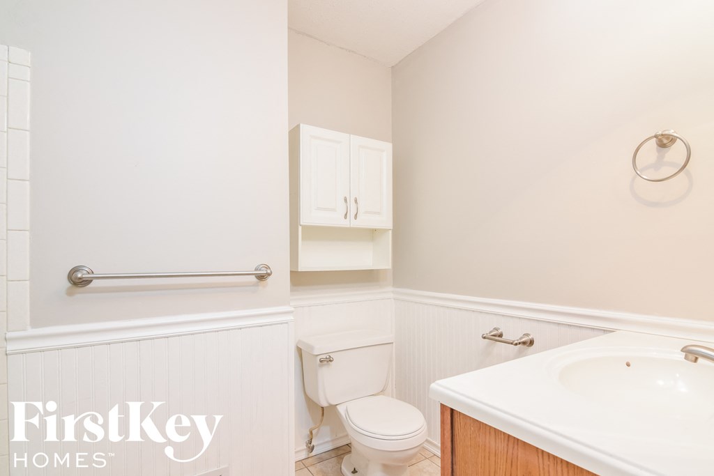A white bathroom with a toilet, sink, and cabinets.